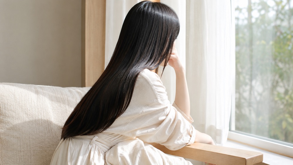 窓辺でくつろぐツヤ黒髪の女性