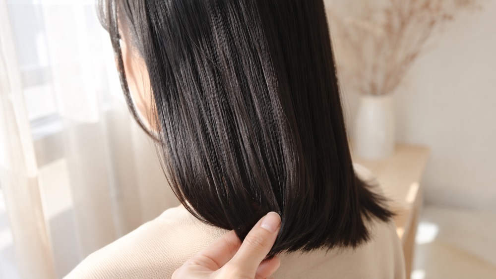 ツヤのある髪の毛先を指先で持つ様子
