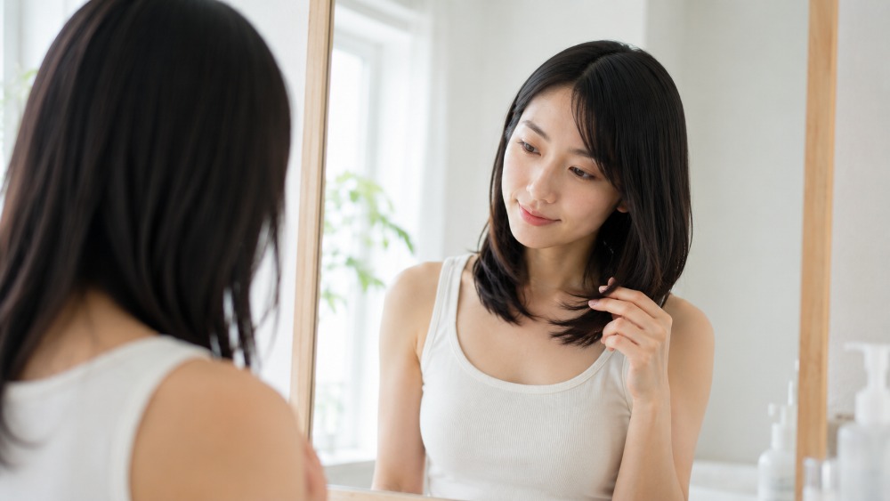 鏡の前で毛先の状態を確認する女性