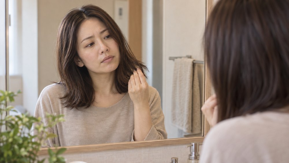 鏡の前で髪について考える女性