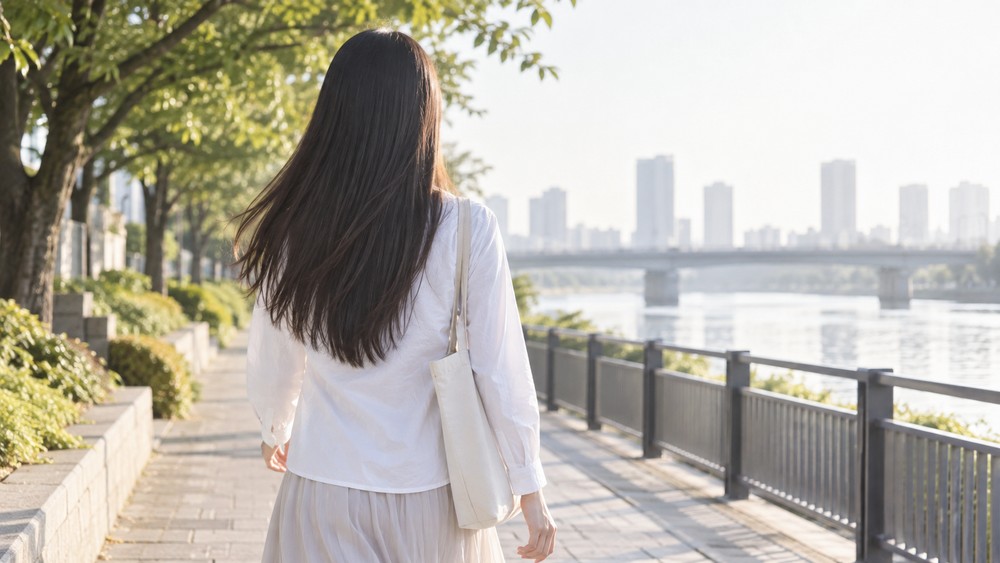 朝の光の中でまっすぐな髪をなびかせて歩く女性