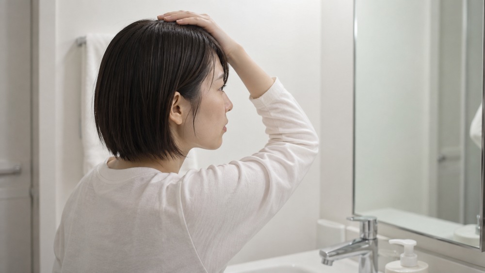 鏡の前でショートヘアのトップのボリュームを確認する女性