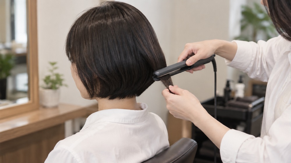 頭の丸みに沿ってショートの毛先へアイロンを入れる様子